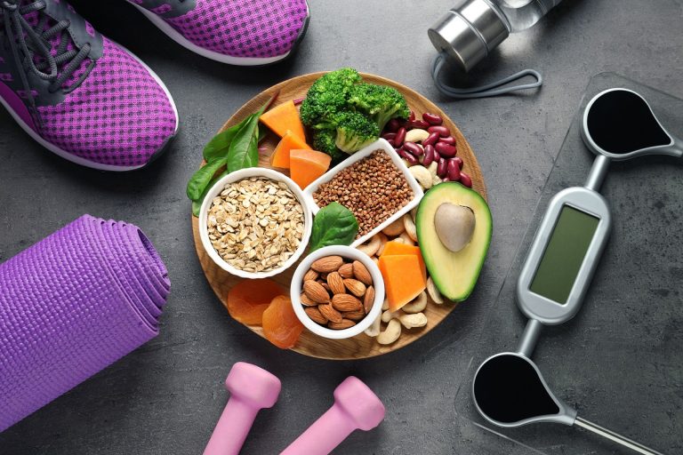 Plate with heart-healthy products and sports equipment on grey b